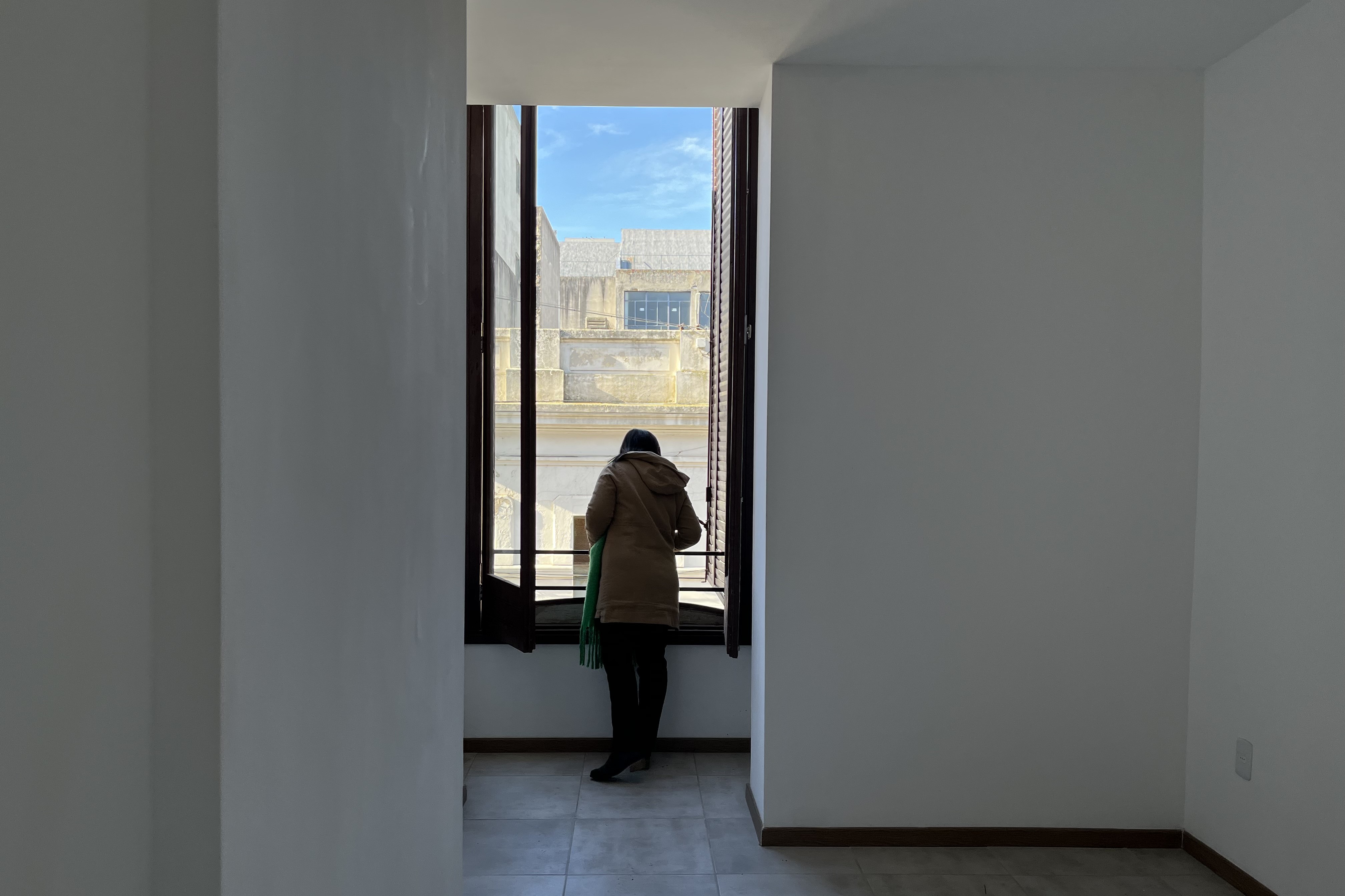 Inquilina en su apartamento mirando por la ventana hacia afuera
