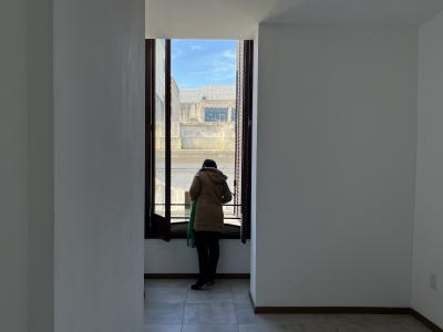 Inquilina en su apartamento mirando por la ventana hacia afuera